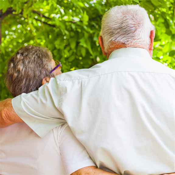photo of two people hugging outdoors with their backs to the camera  